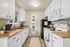 Charming and bright kitchen with classic white cabinets, modern appliances, and warm wooden countertops.