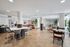 Modern communal living space with elegant wood flooring, a stylish breakfast bar, and cozy seating areas adorned with lush plants.