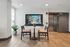 Inviting apartment lobby with stylish seating area, featuring elegant chairs and a marble-top table, accentuated by a modern wall design and a picturesque digital display.