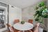 Bright and modern meeting space with a round marble table, stylish leather chairs, and a lush green plant by the window.