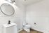 Sleek, modern bathroom with white subway tiles, round mirror, and elegant fixtures.