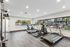 Modern fitness center with state-of-the-art gym equipment and large windows overlooking a vibrant outdoor pool and playground.