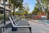 Inviting outdoor pool area with modern loungers and vibrant children's playground, set amidst lush greenery.