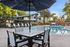 Charming apartment complex with a pristine swimming pool, shaded seating area, and vibrant playground under a sunny sky.