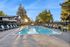 Inviting outdoor pool area with sun loungers, surrounded by lush greenery and vibrant play space, perfect for relaxation and family fun.
