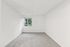Bright and spacious room with fresh, neutral walls and plush carpet, featuring a large window that enhances natural light and offers a pleasant view of greenery outside.