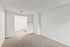 Bright, carpeted room with modern white walls, leading to a hallway with built-in storage. Ideal for a cozy, personalized space.