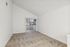 Bright apartment space with vaulted ceiling, fresh carpet, and sliding glass doors leading to a sunlit balcony.