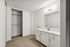 Elegant bathroom vanity with modern sink, bright lighting, and spacious closet in a contemporary apartment.