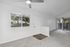 Bright apartment interior with large window, ceiling fan, and sliding door leading to a cozy balcony with scenic views.