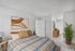 Inviting bedroom with modern decor, featuring a cozy bed with patterned bedding, stylish artwork, and vibrant greenery for a refreshing touch.