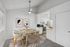 Modern dining area with elegant wooden table, stylish chairs, contemporary art, and adjacent open-concept kitchen with sleek appliances.
