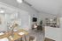 Modern apartment interior showcasing a bright living area with a cozy seating arrangement, elegant dining table set, and a sleek, compact kitchen. Large windows provide abundant natural light and a view of lush greenery.