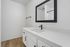 Modern bathroom with sleek white vanity, elegant black fixtures, and a large, stylish mirror.