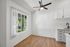 Bright and inviting corner of a modern kitchen area with sleek white cabinetry, elegant wood flooring, and a large window overlooking lush greenery.