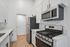 Modern kitchen with sleek stainless steel appliances, white cabinetry, and elegant wood flooring.