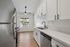 Modern kitchen with sleek white cabinetry, stainless steel appliances, and a bright window view.