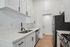 Modern kitchen with sleek white cabinetry, stainless steel appliances, and elegant wood flooring.
