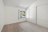 Bright, spacious bedroom featuring cozy carpet flooring and a large window with garden views.
