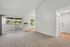 Bright and airy living space featuring plush carpeting, large sliding glass doors opening to a balcony, and an abundance of natural light.
