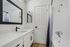 Contemporary bathroom design featuring sleek black fixtures, a large mirror, and a pristine white countertop, offering a modern and stylish space.