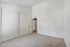 Spacious, well-lit bedroom with plush carpet, modern white sliding closet doors, and a calming neutral palette.
