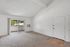 Bright living room with vaulted ceilings, sliding glass door to a private balcony, and cozy carpet flooring.
