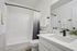 Modern bathroom with elegant white fixtures, sleek vanity, and a stylish shower curtain, enhanced by soft lighting and decorative accents.