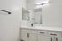 Elegant bathroom with white cabinetry, modern black fixtures, and illuminated mirror offering a sleek and contemporary feel.