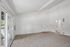 Inviting living area with plush carpeting, high ceilings, and abundant natural light from the sliding glass door.