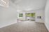 Bright living area with large windows and sliding doors leading to a balcony, complemented by plush carpeting and neutral walls.