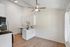 Modern kitchen with sleek white cabinetry, elegant countertops, and stainless steel appliances, complemented by stylish lighting and warm wood flooring.