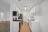 Sleek modern kitchen with stainless steel appliances, bright white cabinetry, and elegant wood flooring.