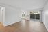 Bright and airy living space with wood flooring, a large sliding glass door leading to a private patio, and clean white walls, perfect for modern living.