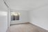 Bright and airy empty room with plush carpeting, large window, and fresh white walls, offering a cozy and tranquil space.