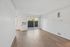 Bright and airy living room with sleek hardwood floors, large sliding glass doors, and modern wall-mounted air conditioning unit.