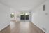 Bright and airy living space with large windows, sleek wood flooring, and a sliding glass door opening to a private patio.
