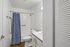 Modern bathroom with sleek fixtures, elegant white cabinetry, and a stylish blue shower curtain for a fresh, inviting atmosphere.