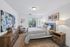 Chic bedroom with modern decor, featuring a stylish bed, cozy armchair, and large window for natural light.