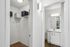 Contemporary walk-in closet with open shelving next to a sleek modern bathroom featuring elegant vanity lighting.