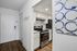 Chic and modern kitchen with stainless steel appliances, white cabinetry, and stylish backsplash artfully showcased in a cozy apartment entryway.
