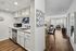 Bright and stylish open-concept apartment featuring a modern kitchen with sleek cabinetry and a spacious living area with elegant wood flooring and large windows.