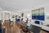 Modern apartment interior with open-concept living and dining area, featuring stylish blue decor, elegant artwork, and a cozy seating arrangement.