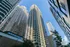 Striking upward view of modern high-rise buildings with sleek windows under a clear blue sky, showcasing urban architectural elegance.