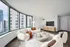 Modern living room with elegant curved windows offering a stunning city view, featuring plush white seating and stylish decor.