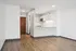 Sleek modern apartment with an open-concept kitchen featuring stainless steel appliances, bright white cabinetry, and elegant wood flooring.