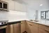 Modern kitchen with sleek stainless steel appliances, elegant white countertops, and ample natural light from large windows.