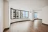 Bright, spacious apartment living area with elegant wooden flooring and large windows offering stunning city and water views.