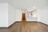 Modern apartment interior with sleek wooden floors, bright white walls, and an open kitchen featuring stainless steel appliances.