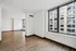 Bright, spacious room with modern wood flooring and large windows offering a stunning cityscape view.